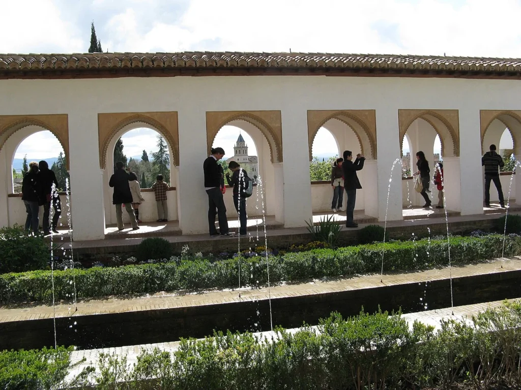 Canal de agua y surtidores junto a una galería de arcos y jardines del Generalife, Granada.