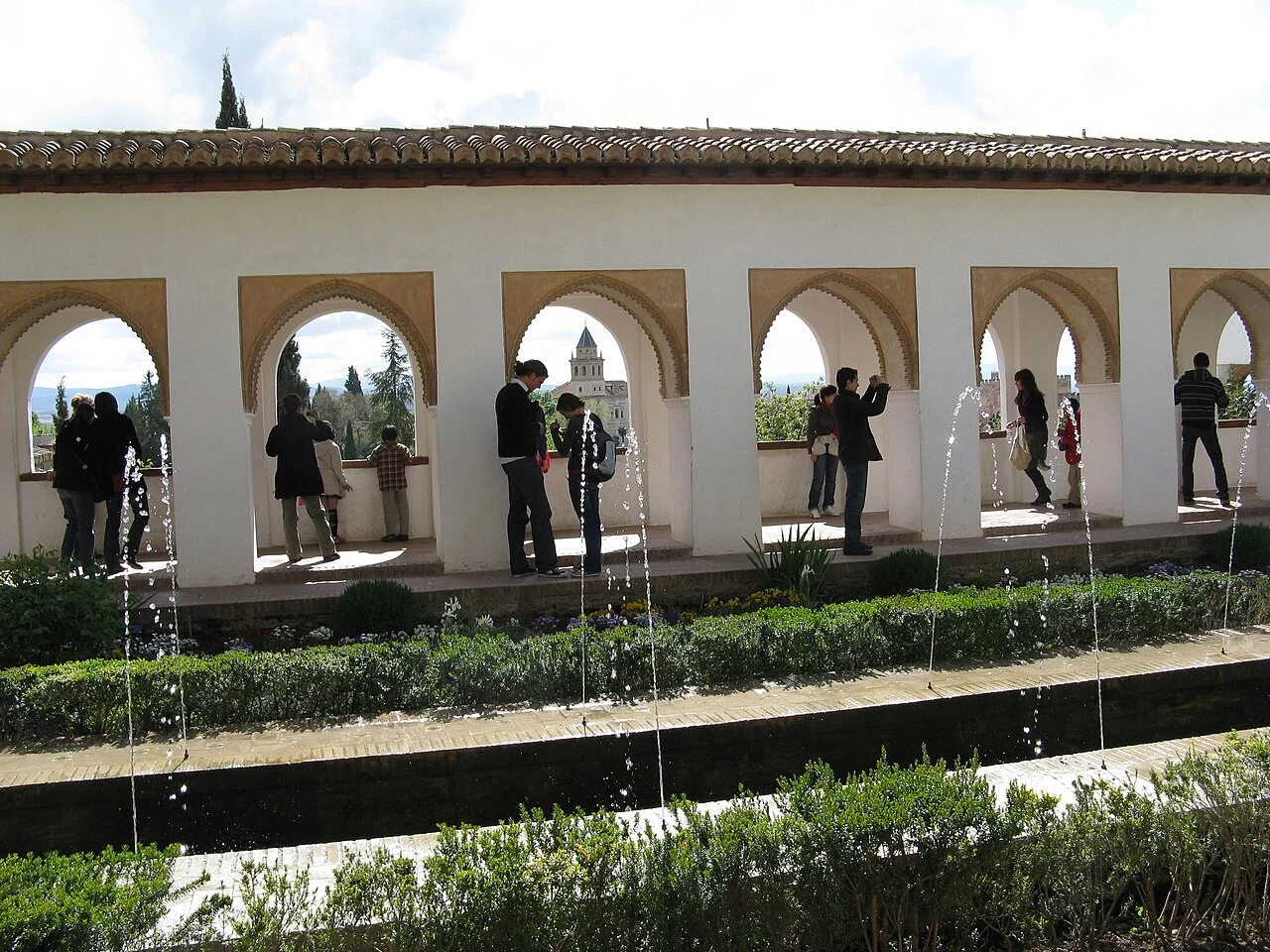 Canal de agua y surtidores junto a una galería de arcos y jardines del Generalife, Granada.