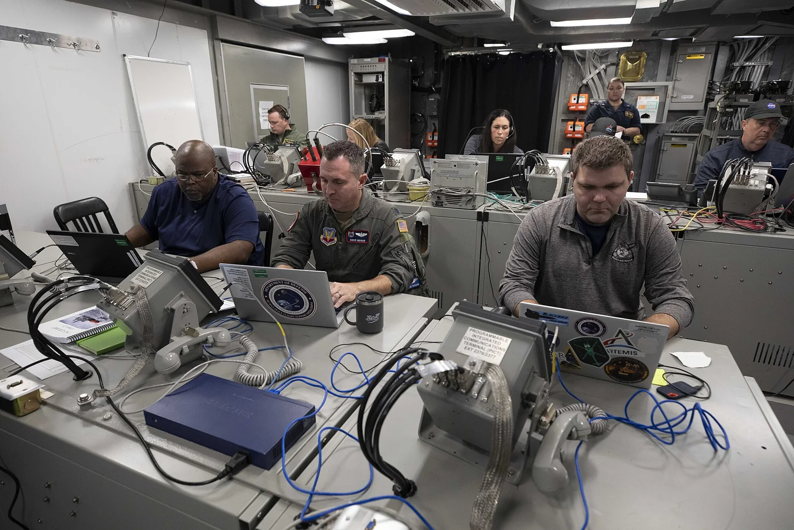 Equipo de recuperación de la NASA en una sala de control del USS Portland.