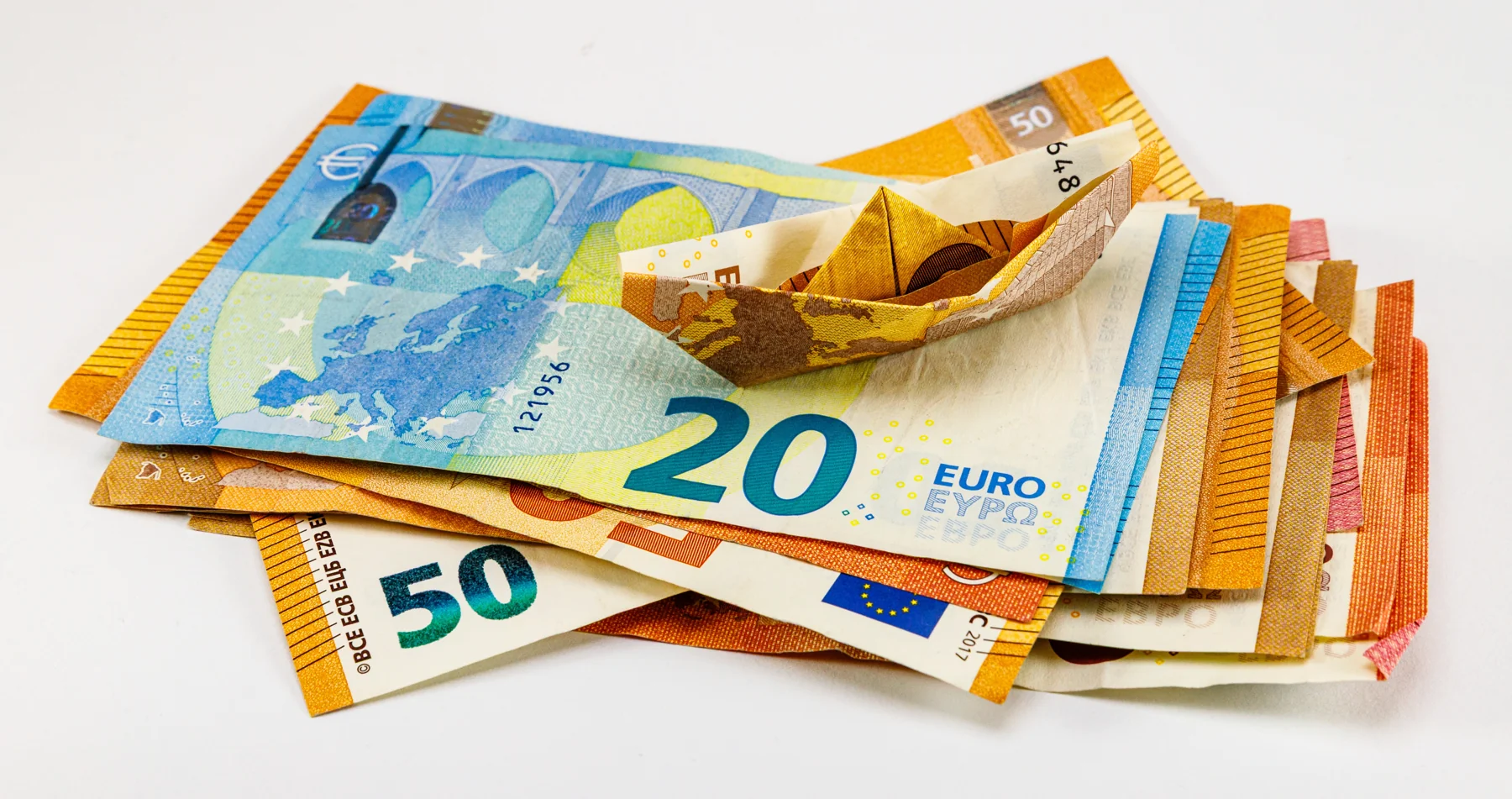 Billetes de euro, con uno doblado en forma de barco.