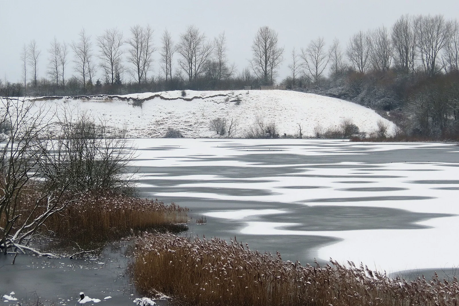 Superficie de un lago parcialmente cubierta de hielo y nieve.