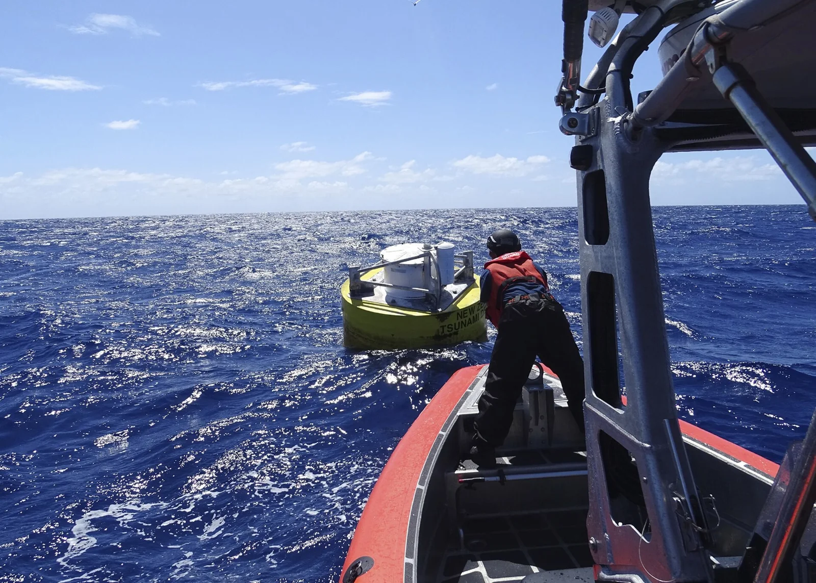 Personal de un buque inspecciona una boya de medición de tsunamis.