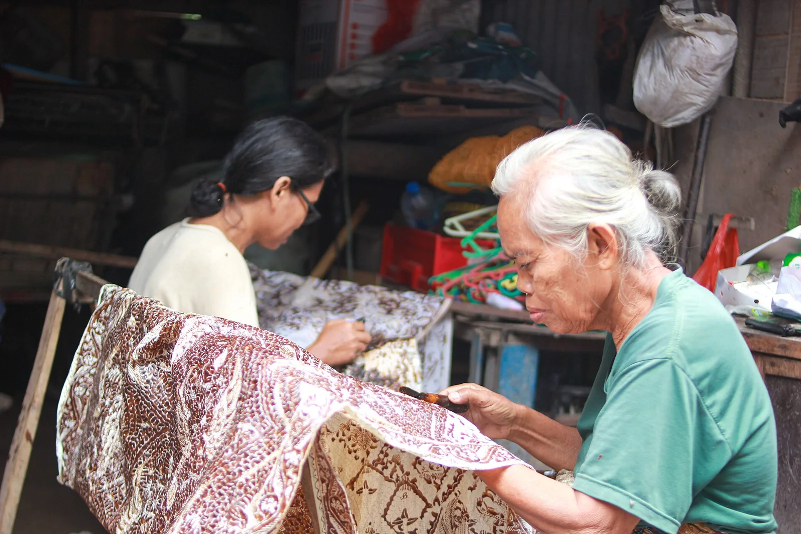 Dos artesanas trabajan con telas de batik en un taller.