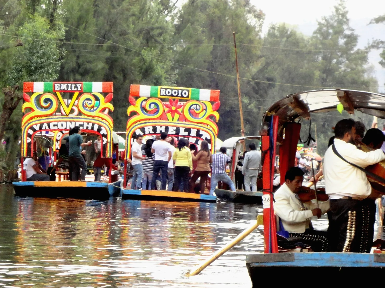 Músicos de mariachi junto a trajineras de Xochimilco.
