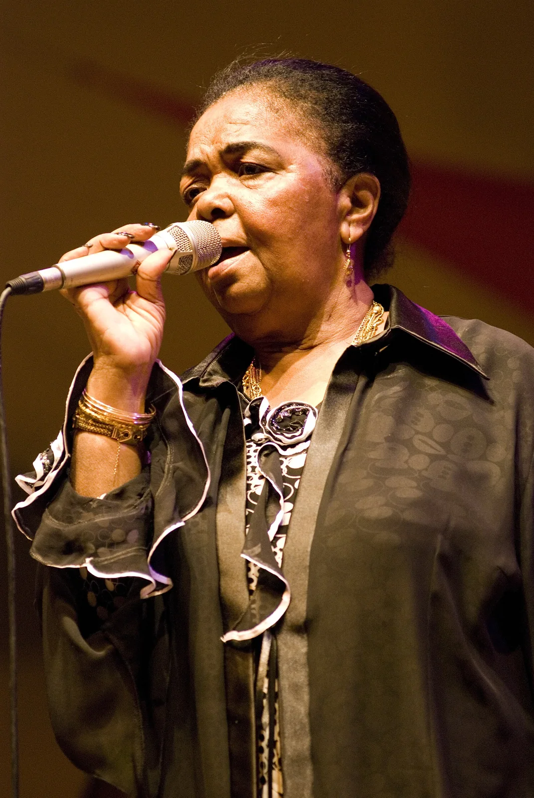 Cesária Évora cantando ante un micrófono.