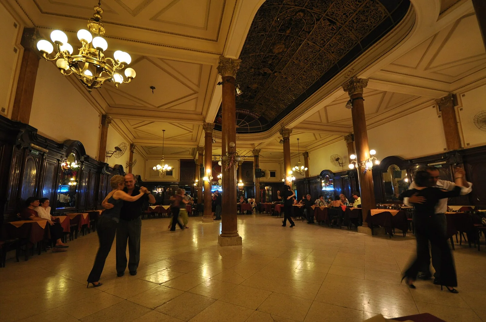 Parejas bailando tango en un salón.
