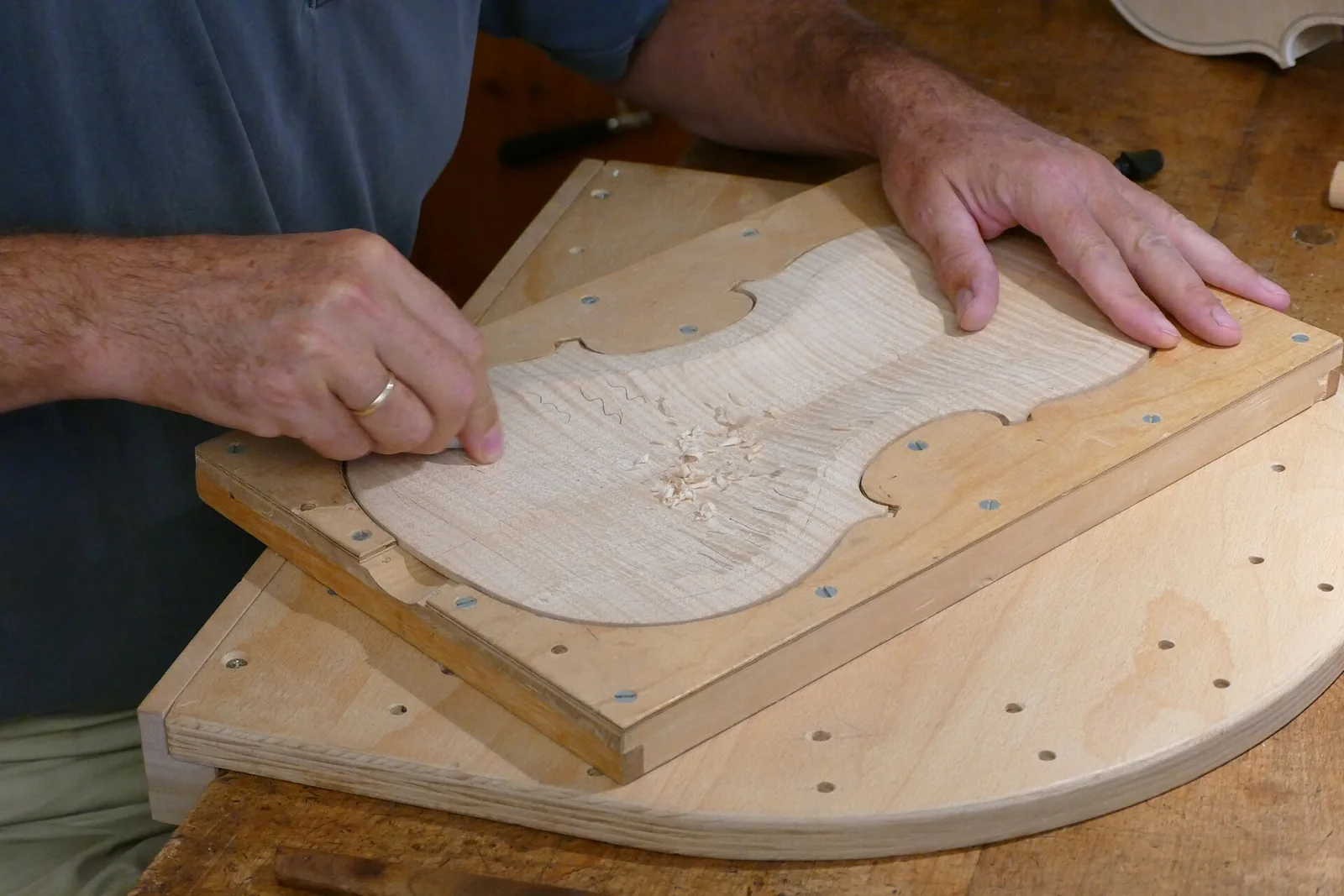 Un lutier trabaja la madera del fondo de un violín.