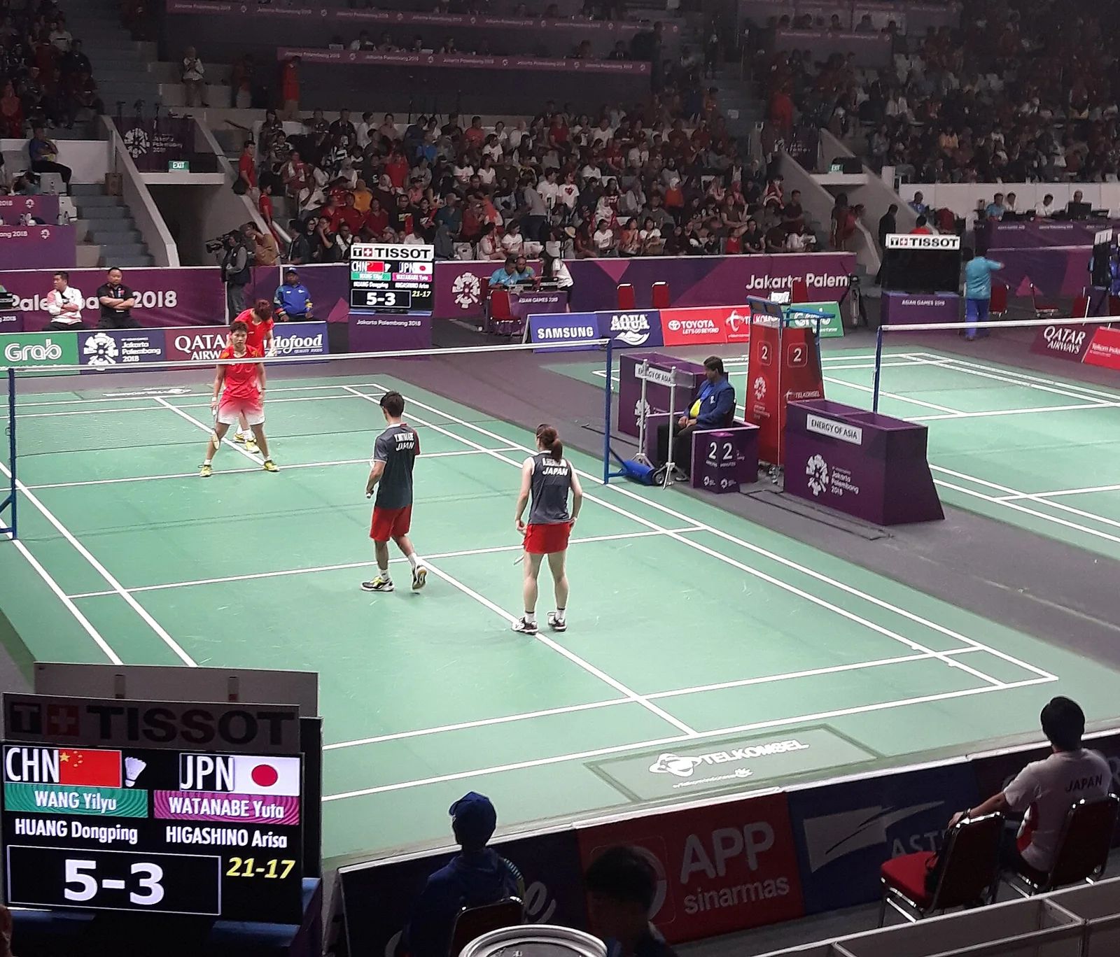 Jugadores de bádminton compiten sobre una pista marcada.