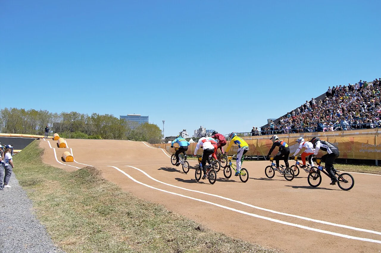 Corredores de BMX Racing compiten sobre un circuito.