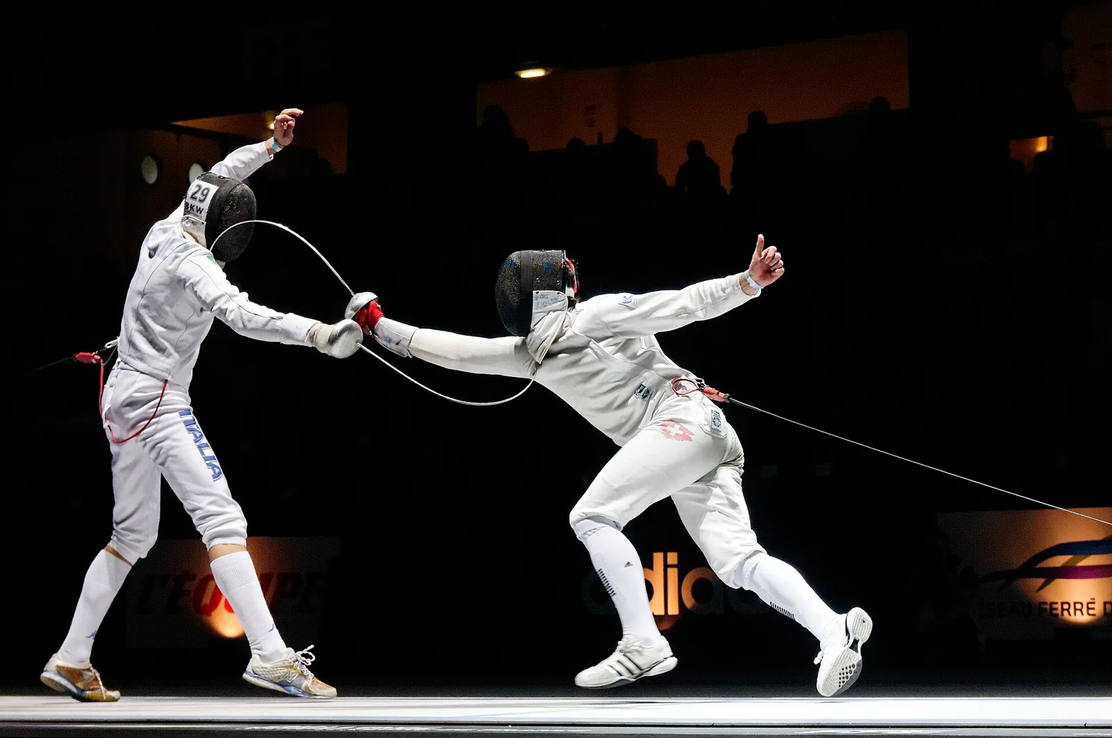 Dos tiradores de espada se enfrentan en una pista de esgrima.