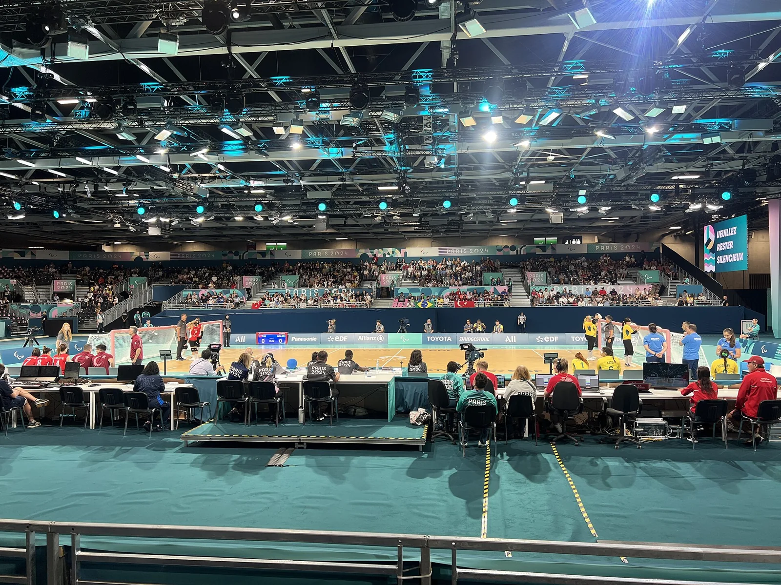Equipos de goalball disputan un partido sobre una pista cubierta.