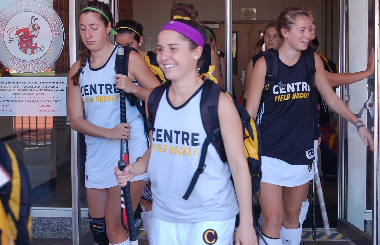 Jugadoras de hockey sobre hierba caminan con sus sticks antes de un encuentro.