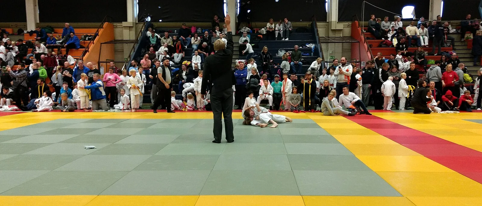 Un árbitro señala el final de una acción de judo junto a los competidores.