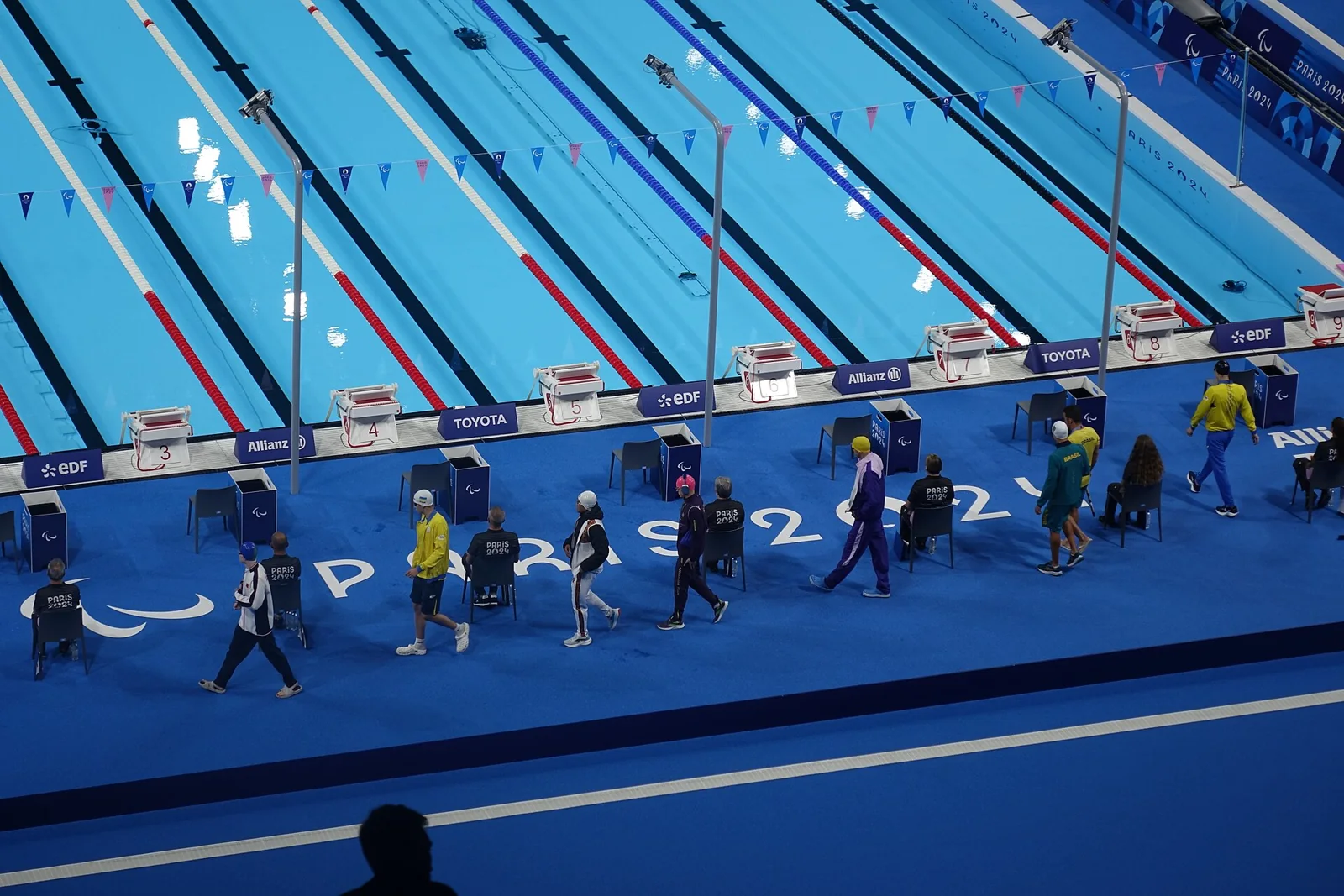 Nadadores se preparan junto a la piscina para una prueba de espalda.