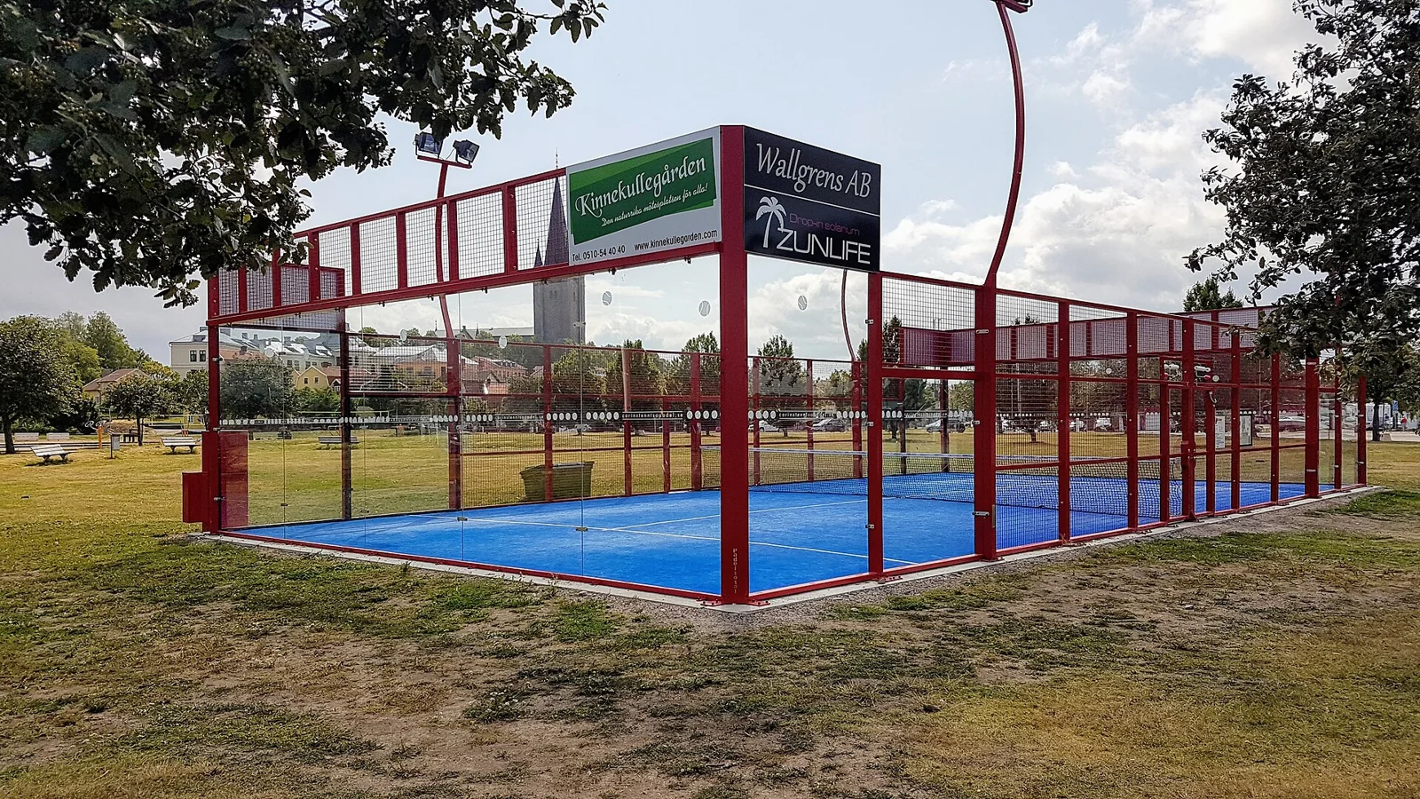 Pista de pádel al aire libre con cerramientos transparentes.