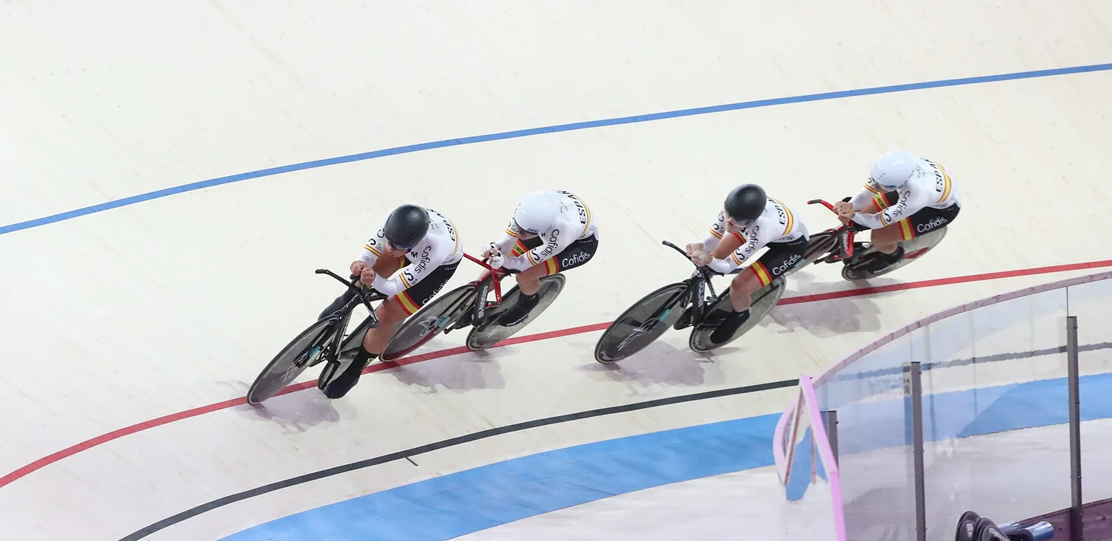 Ciclistas de un equipo compiten en un velódromo.