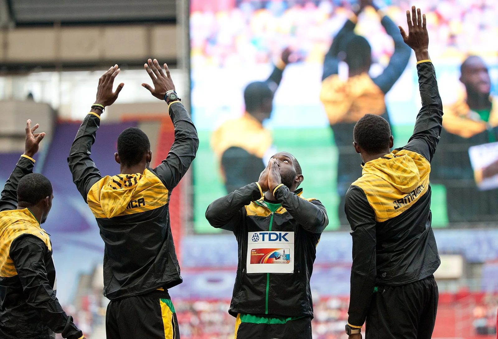Integrantes de un equipo de relevos de atletismo saludan al público.