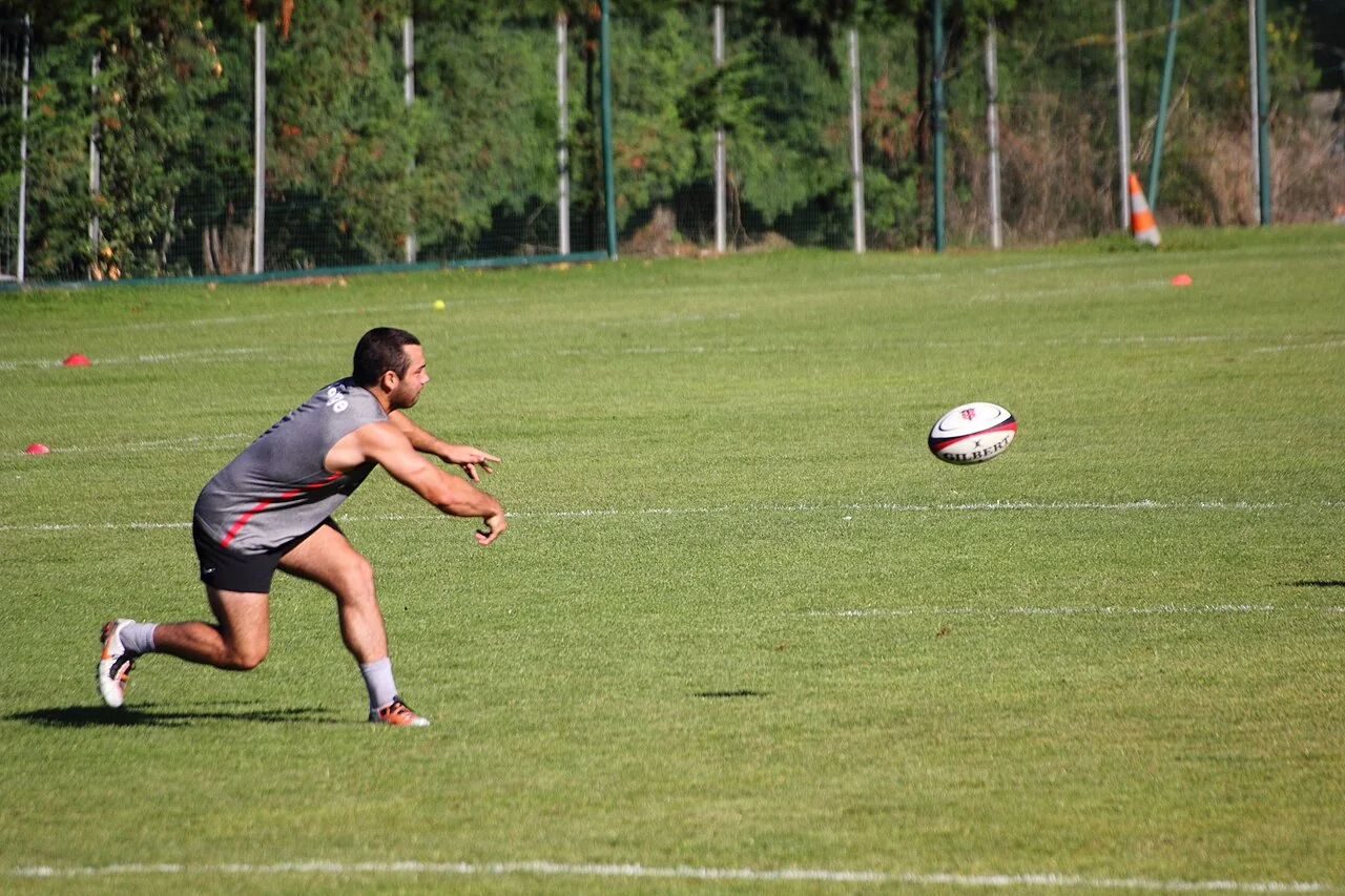 Un jugador de rugby realiza un pase con las manos.