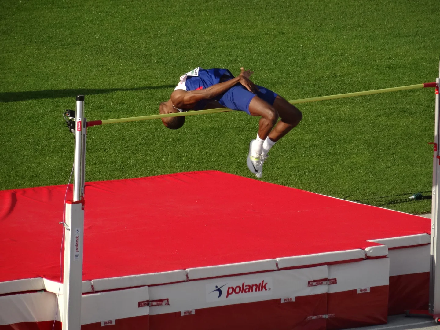 Un atleta franquea el listón de salto de altura.