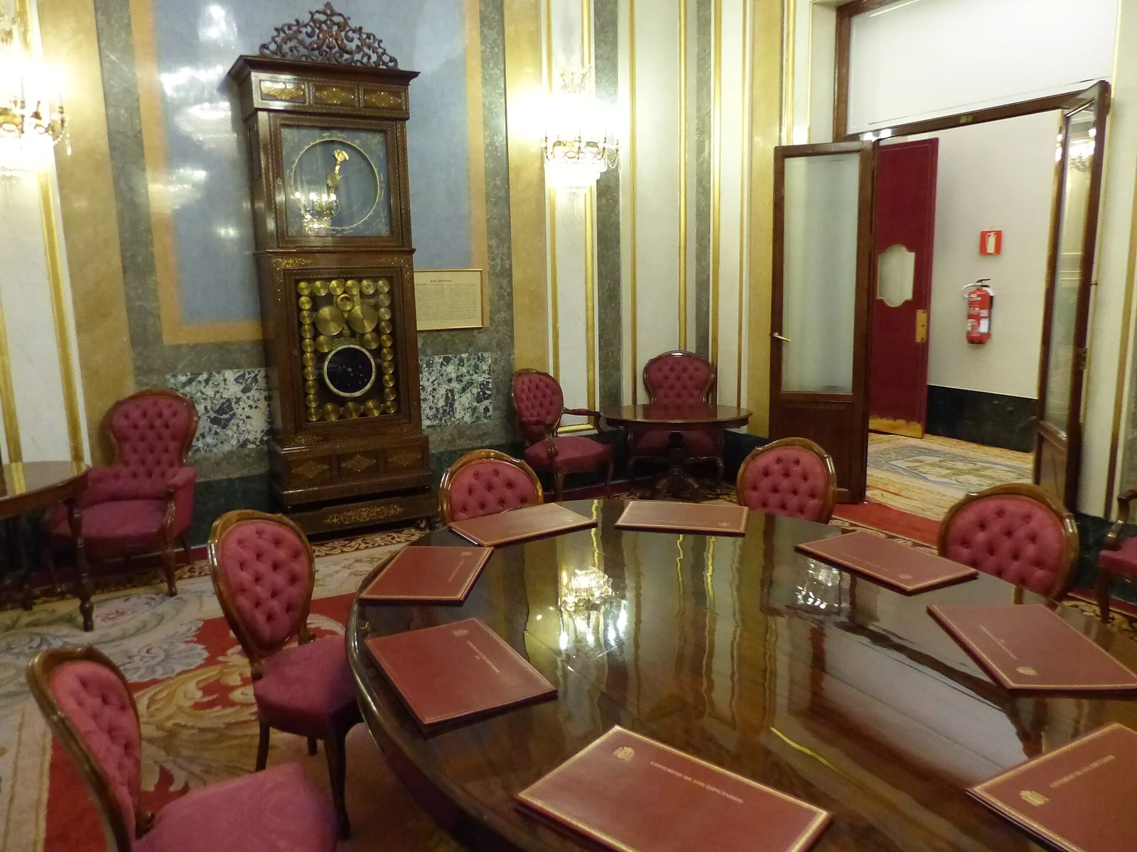 Sala del reloj del Congreso, con sillones y un reloj alto al fondo.