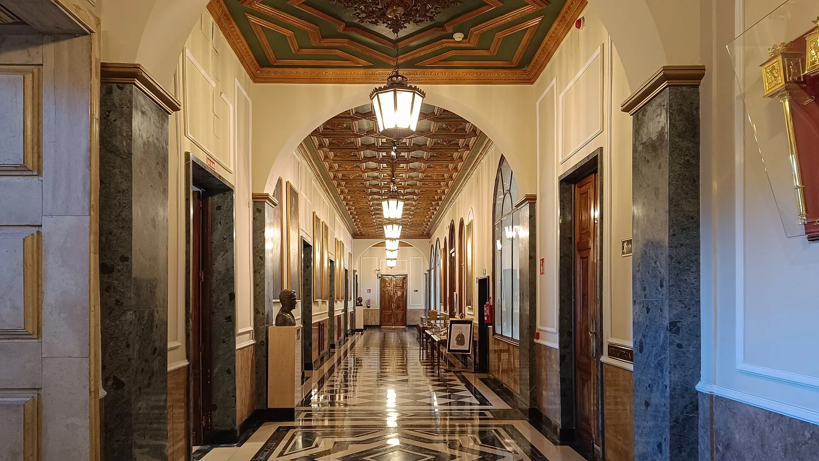 Pasillo interior del Palacio del Senado con cuadros y lámparas.