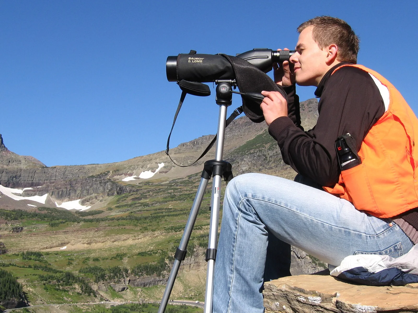 Una persona observa las montañas con un instrumento óptico.