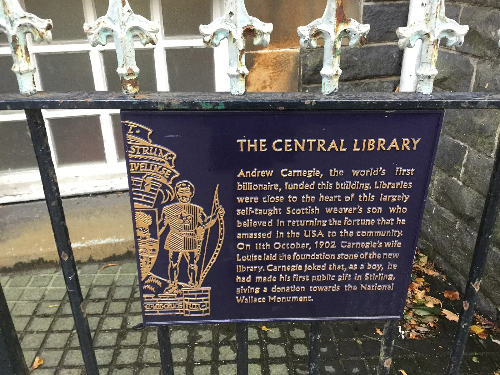 Cartel de información histórica junto a la entrada de una biblioteca.