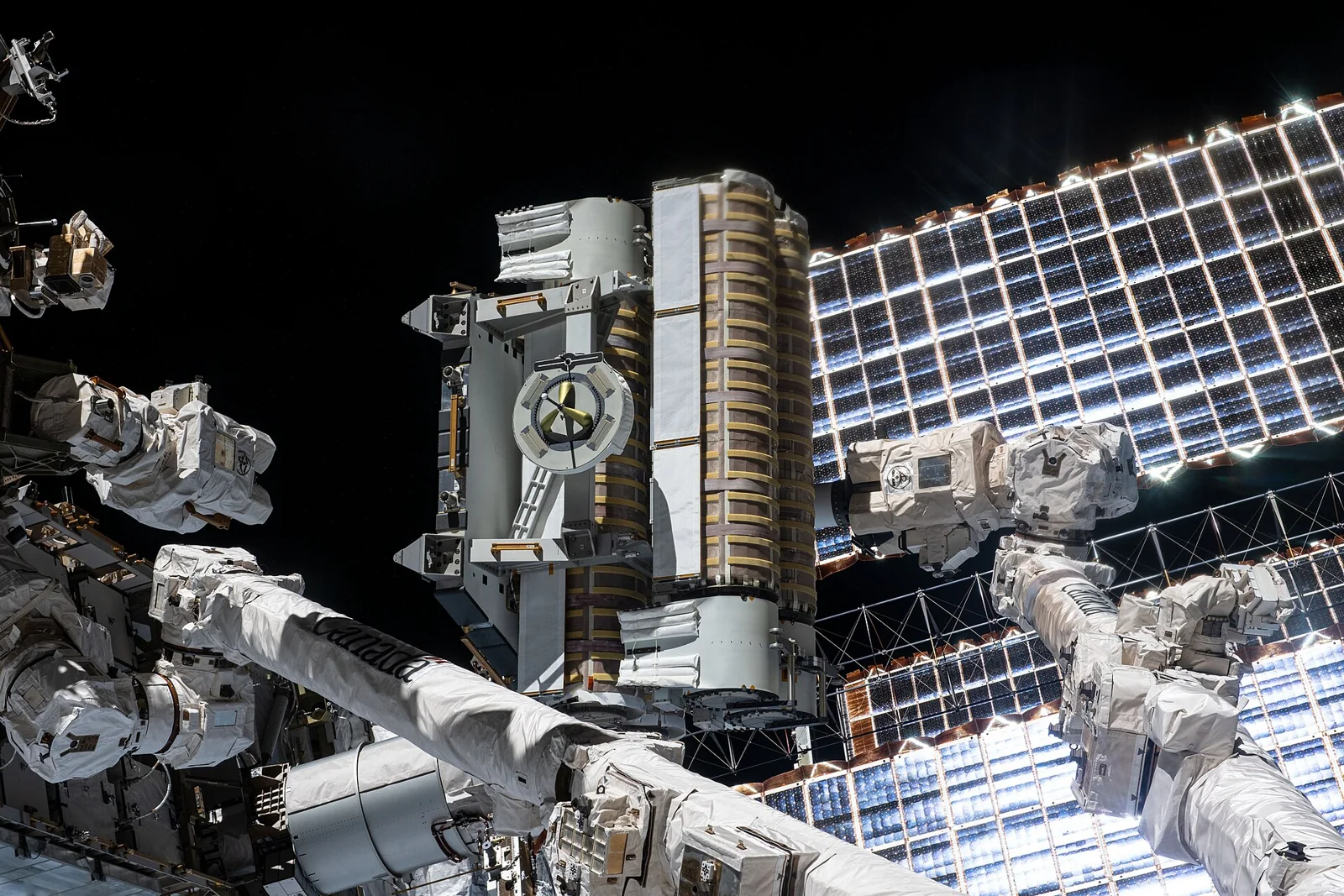 Panel solar iROSA sujeto por el brazo robótico Canadarm2 junto a la estación espacial