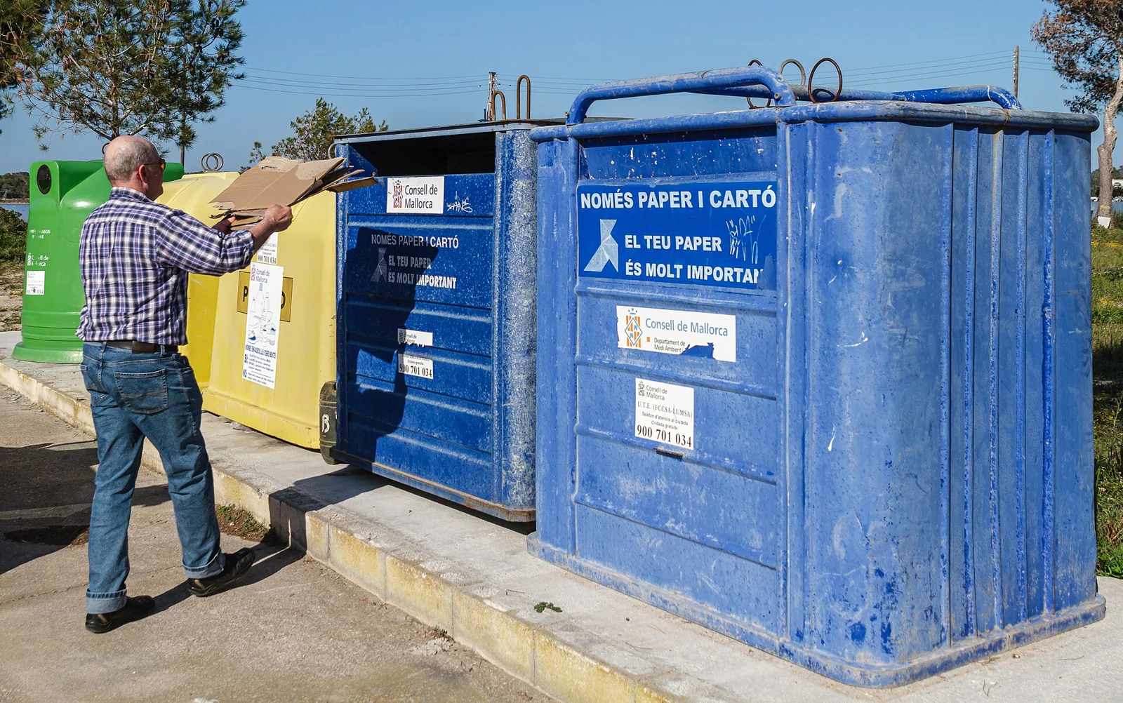 Una persona deposita cartón en un contenedor de reciclaje en Mallorca